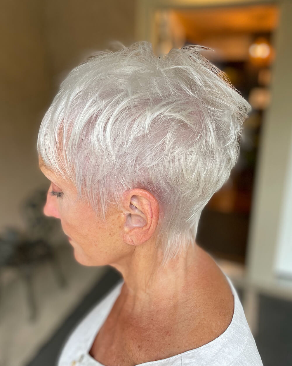 Side view of a bright white textured pixie on an older woman