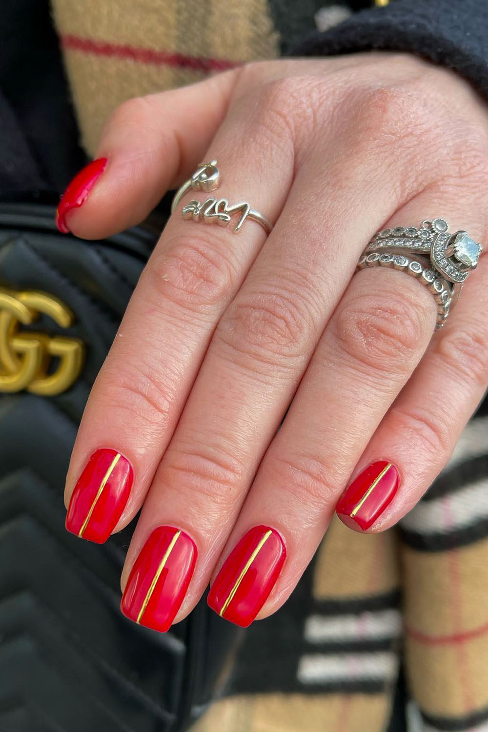 Glossy red nails with minimal thin gold vertical line art
