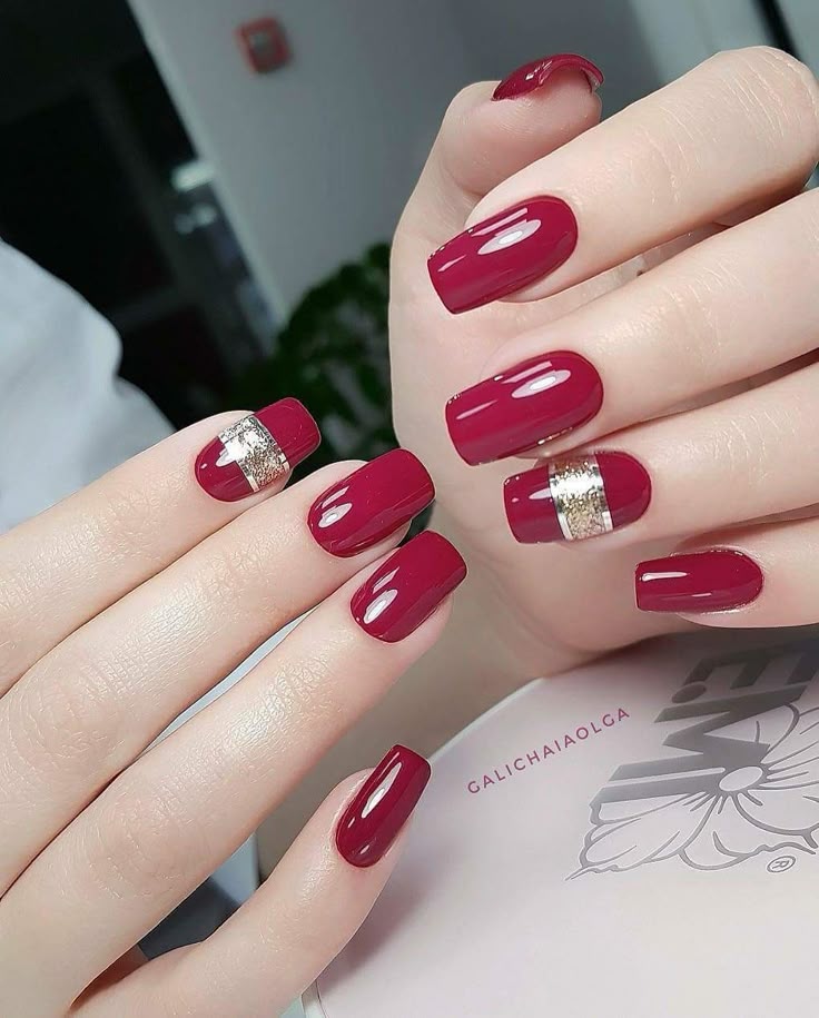 Short oval cherry red nails with gold glitter band accents