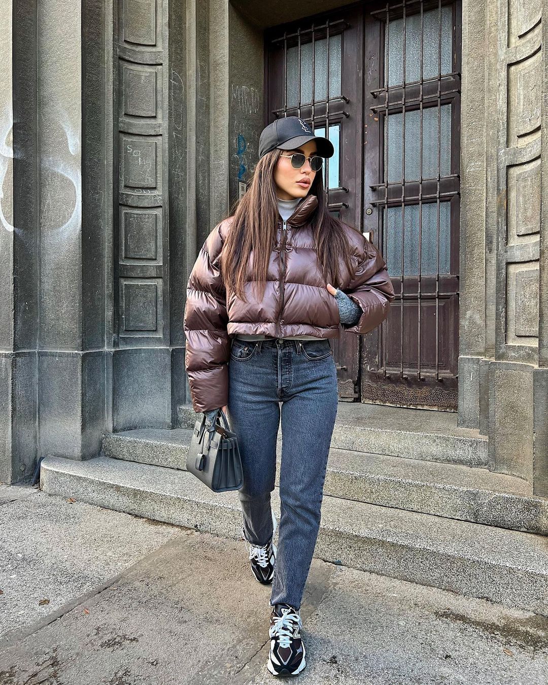Woman wearing a short cropped puffer jacket with high-waisted jeans in winter