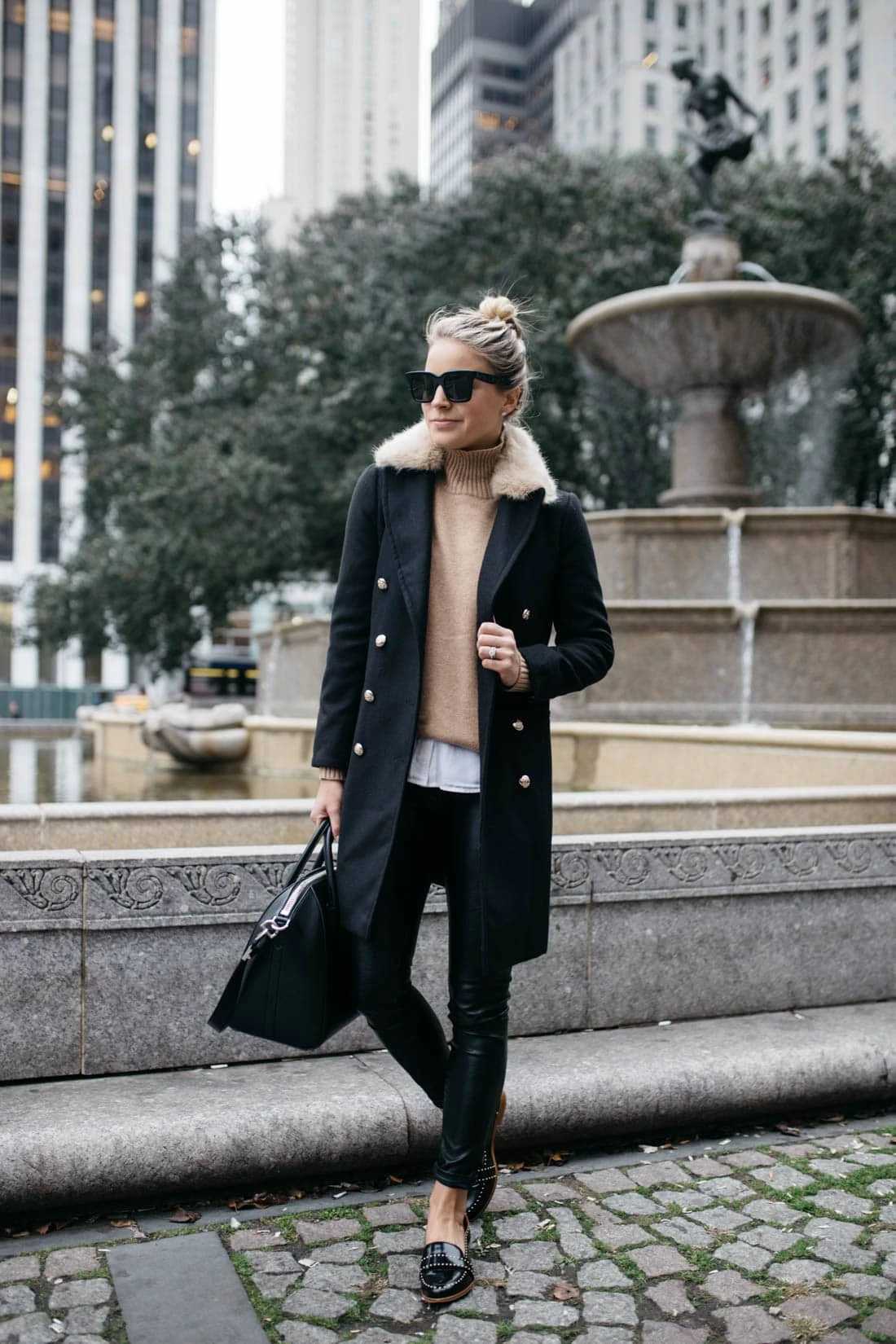 Woman wearing a black coat with a faux fur collar and camel turtleneck evening winter outfit