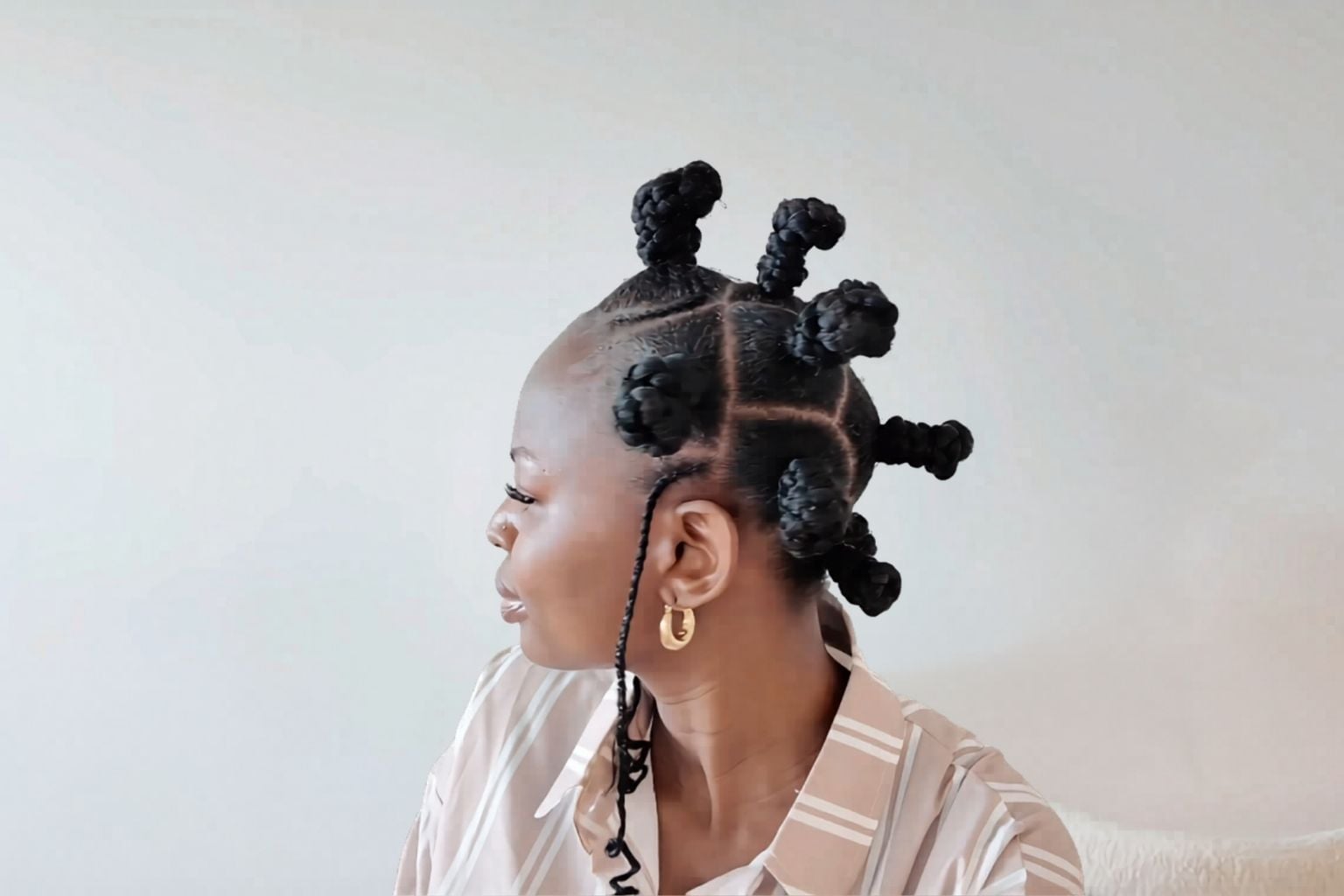 Multiple bantu knots with neat box partings and a thin braided tendril