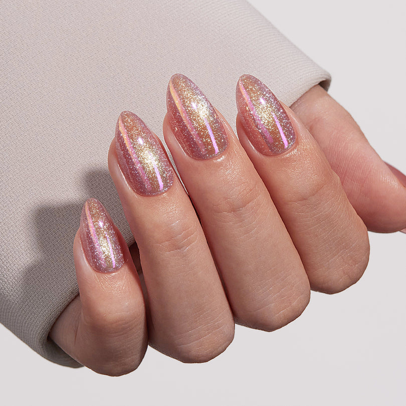 Pink cat-eye press-on nails with firework designs shown on a hand model