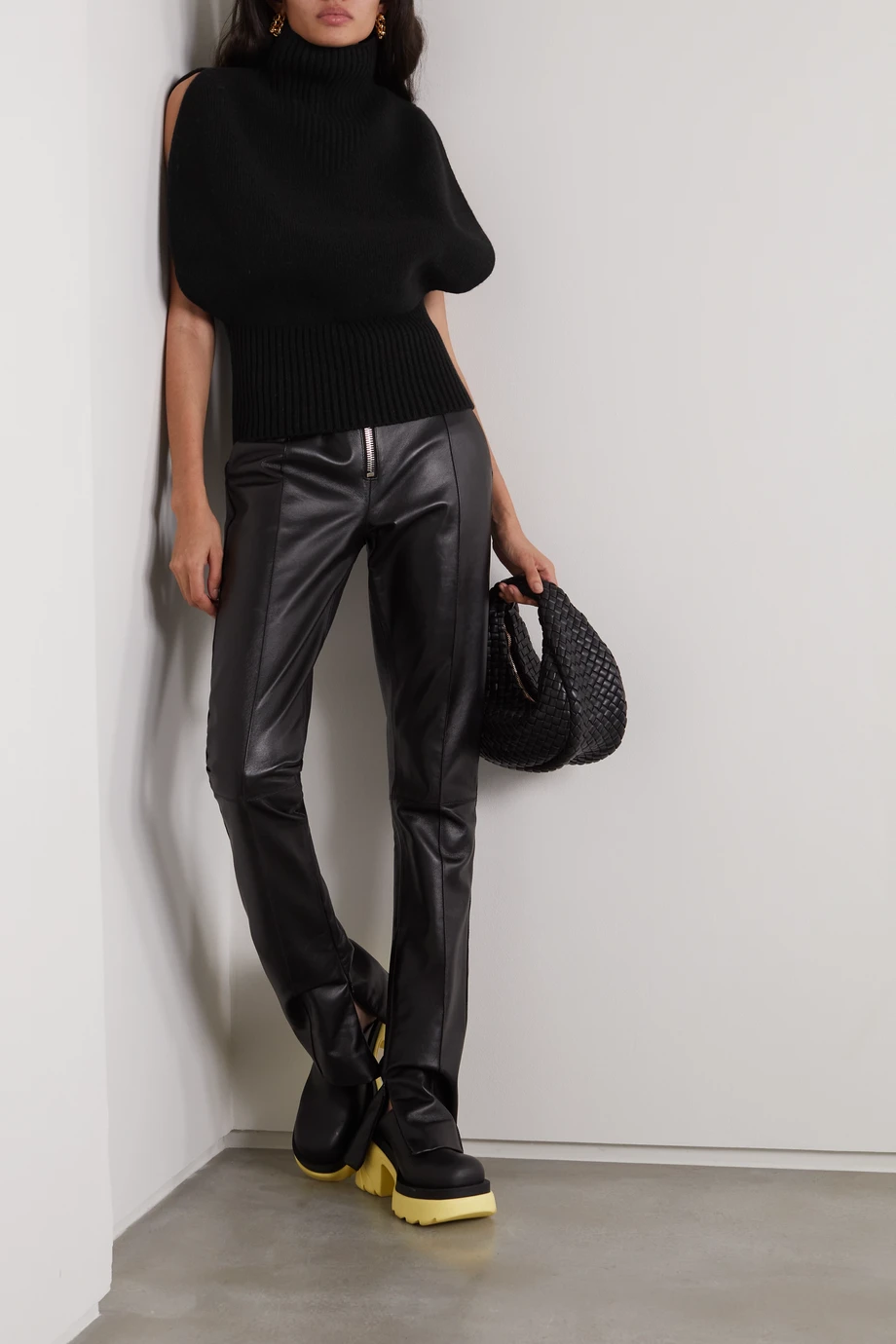 Woman wearing a black sleeveless turtleneck knit top with black leather pants and chunky boots