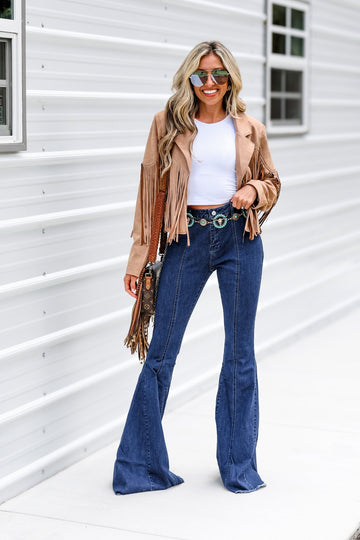Woman wearing a tan suede fringe jacket with bell-bottom jeans