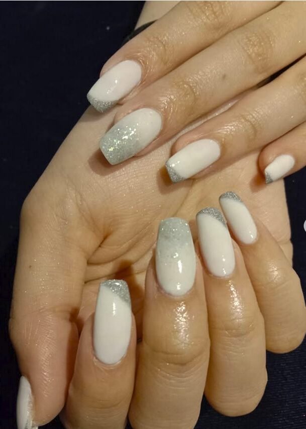 Milky white dip nails with silver glitter fading from the tips toward the cuticle on medium almond nails