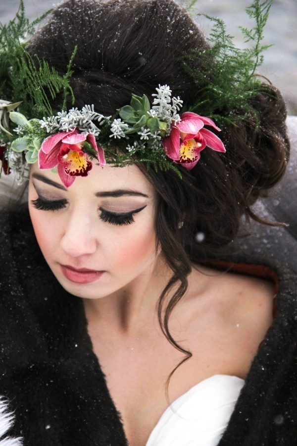 Winter bride wearing an updo with a pink orchid and greenery floral crown in the snow