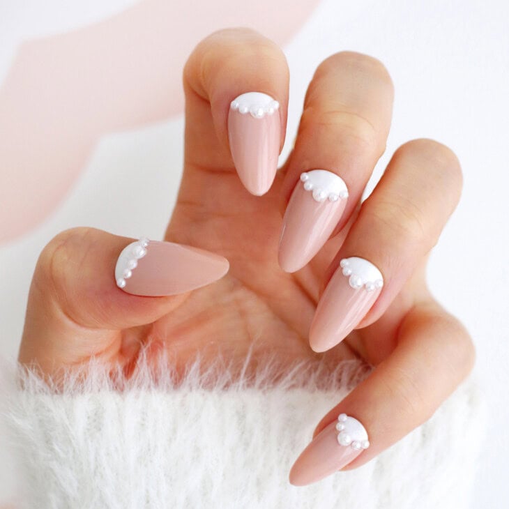 Nude almond nails with white french tips edged in a scalloped row of tiny pearls