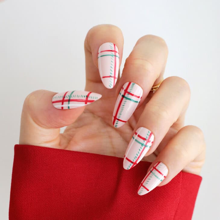 Red and green tartan plaid nail art on sheer white almond nails