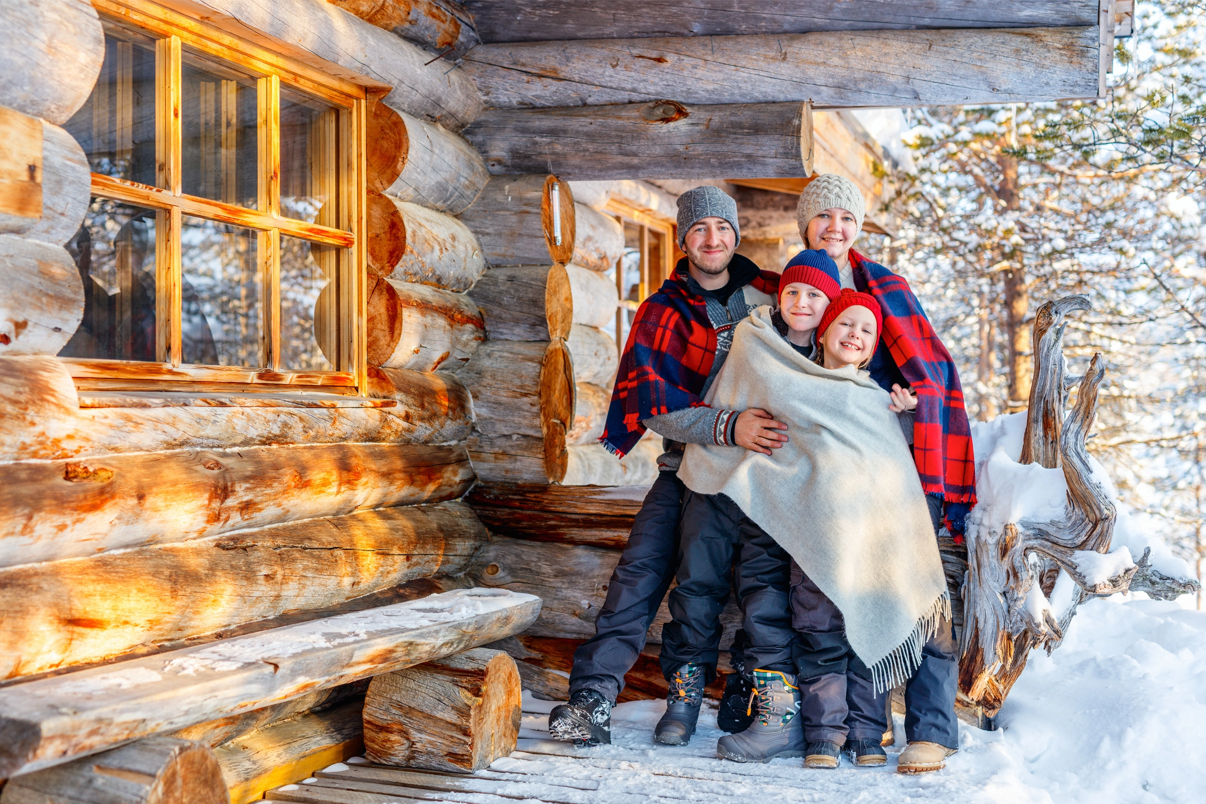 Family in flannel shirts at a log cabin winter photoshoot