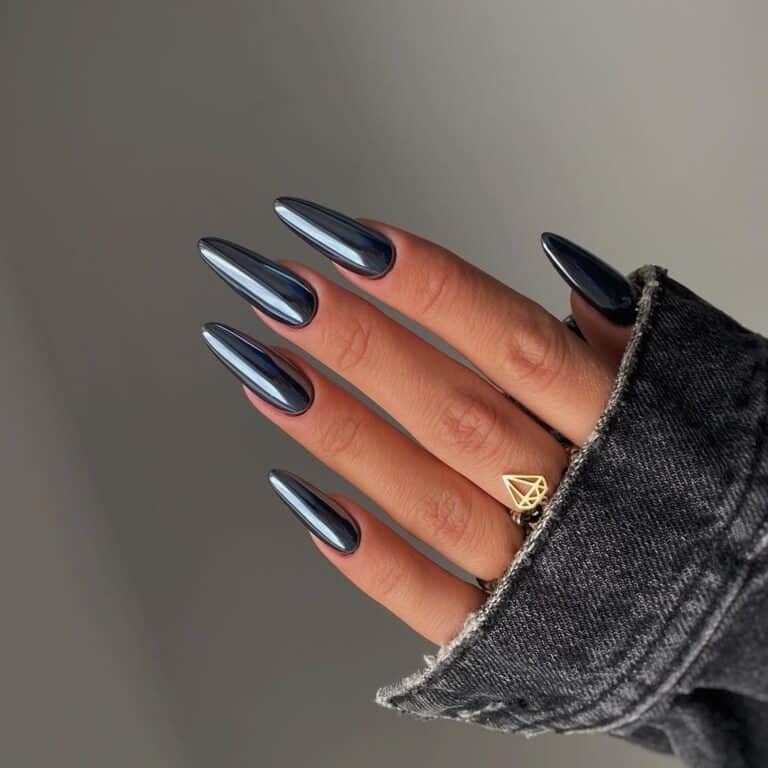 Long charcoal-gray stiletto nails with an iridescent gunmetal chrome sheen catching the light.