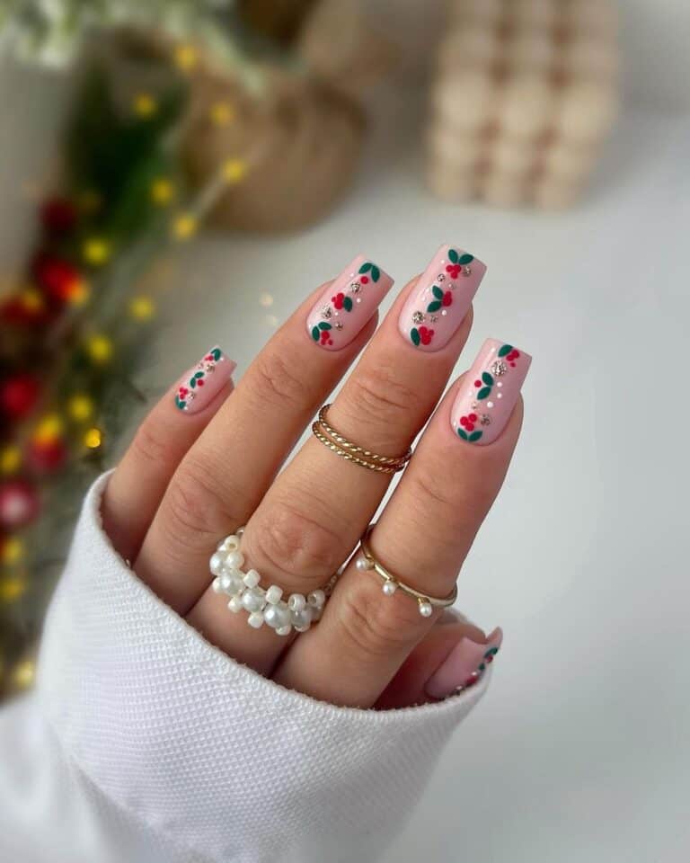 Long square nails in pale pink with hand-painted holly leaves, berries, and rhinestones.