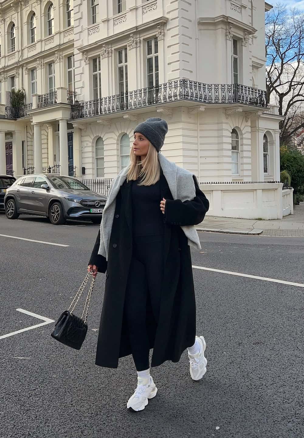 Woman wearing a long coat with leggings and sneakers