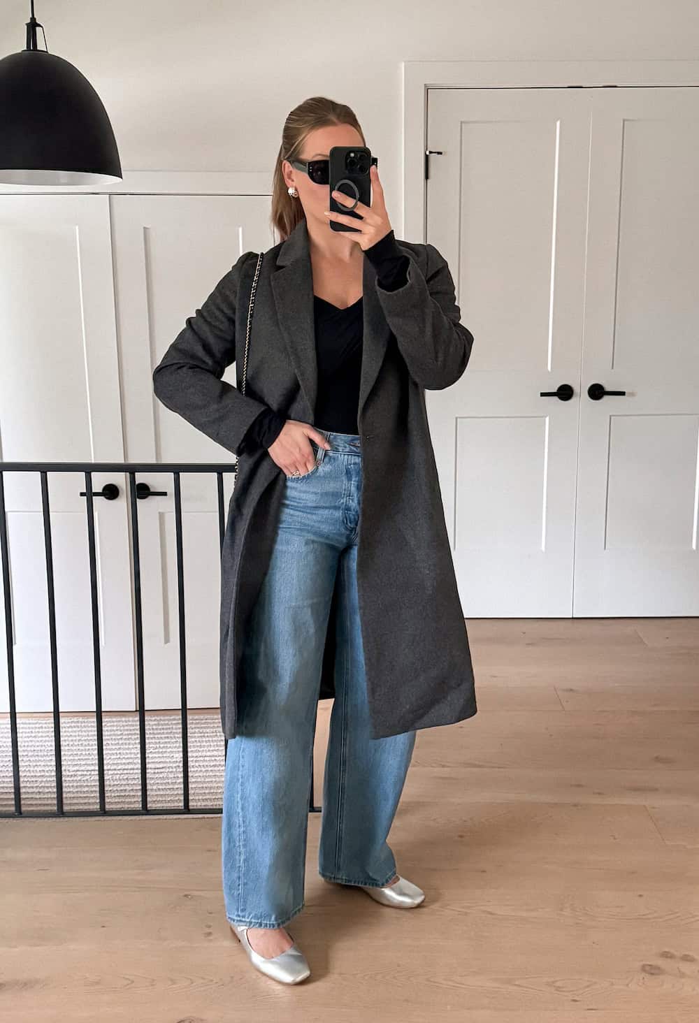 Woman wearing a long charcoal wool coat with jeans and silver ballet flats