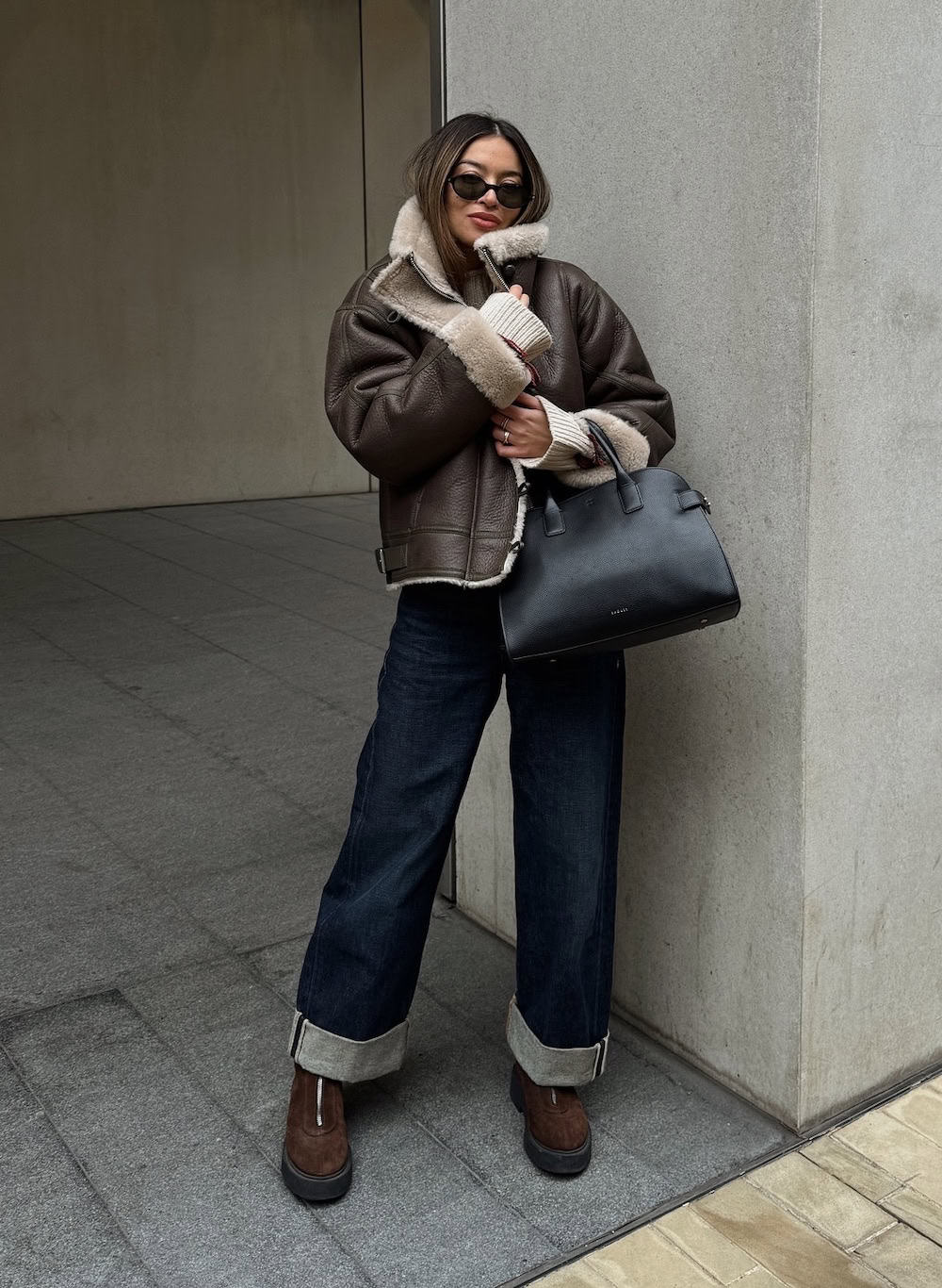 Woman wearing a leather aviator jacket with cuffed jeans and chunky boots