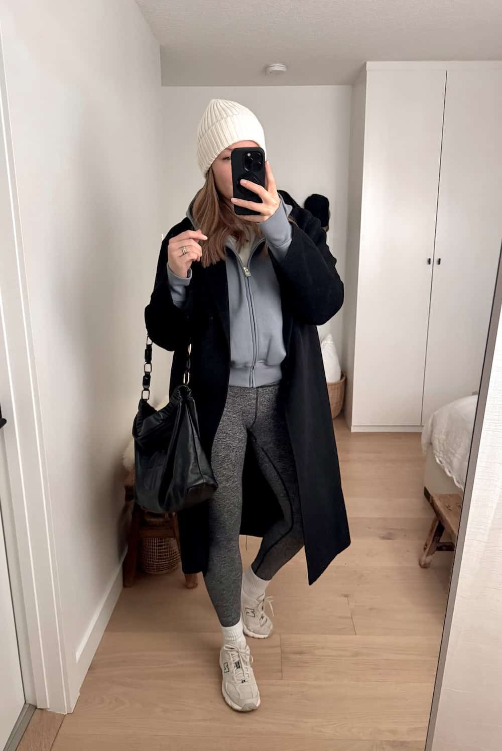 Woman wearing a matching sweat set with a wool coat and sneakers