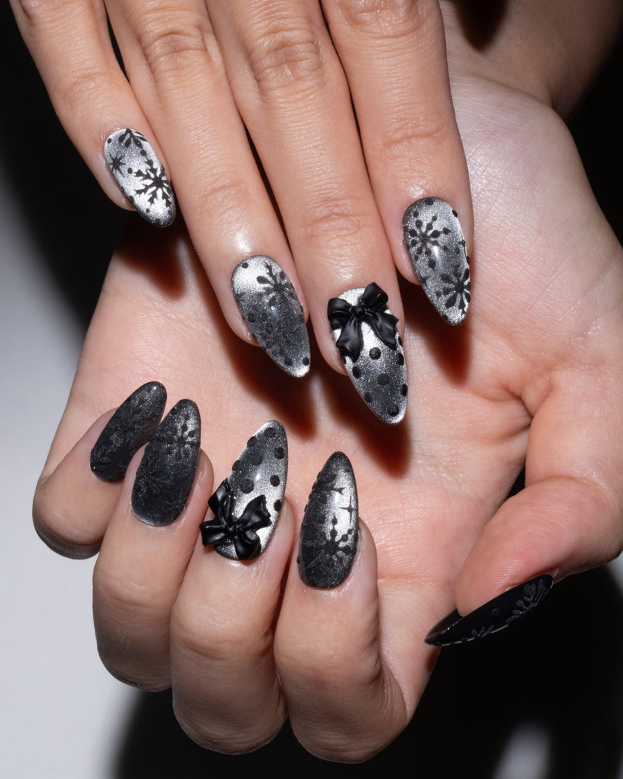 Stiletto nails in black and silver chrome with black 3D bows and snowflake accents