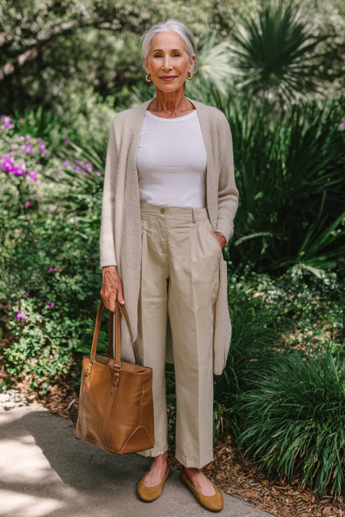 Older woman in a white shirt layered under a camel cashmere cardigan with dark trousers