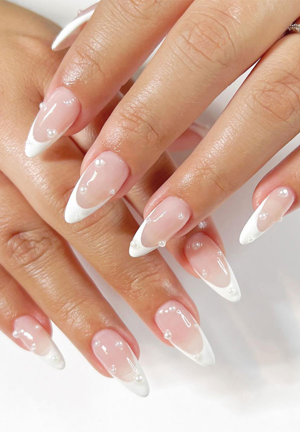 White French tips on almond nails dotted with tiny pearl accents