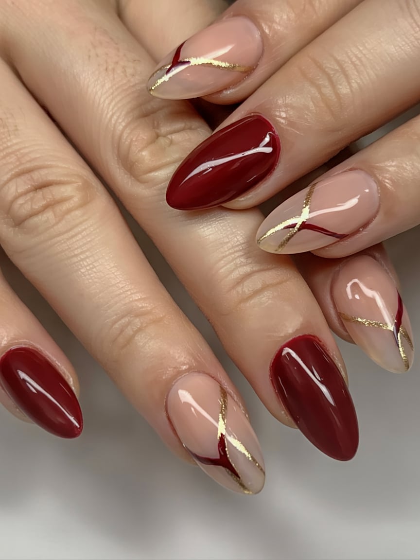 Almond nails in burgundy and nude with red and gold geometric line art